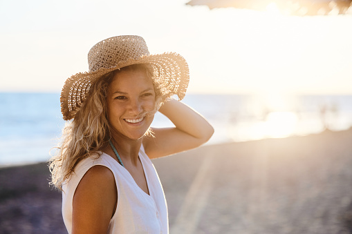 Portrait of happy woman with sun hat enjoying in summer day on the beach. Copy space.
