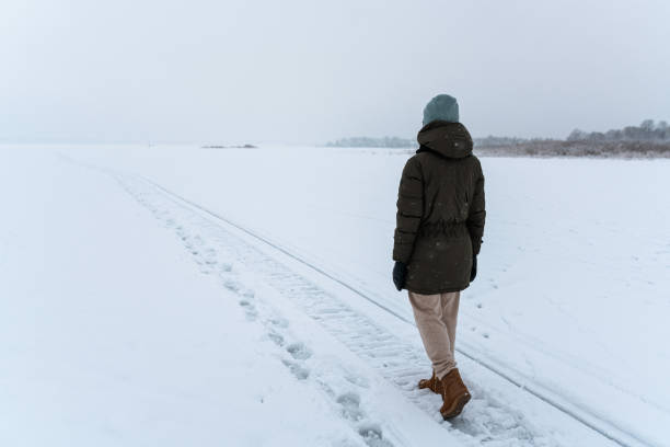 istock Woman walking alone in misty winter field 1445113708