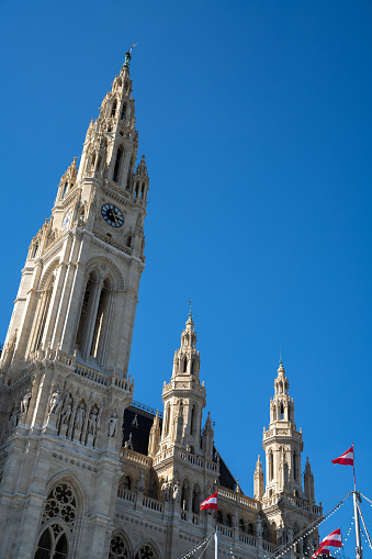 Vienna, Austria - 22 September, 2022: the Vienna city hall building under a blue sky with Austrian flags in the foreground