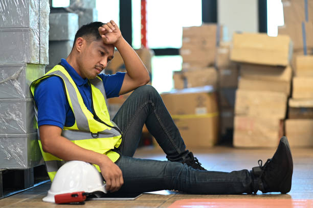 istock Tired male warehouse worker sitting on floor and taking break from hard work in large retail warehouse. 1445119392