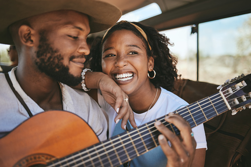 Guitar, music and happy couple on a car road trip together on a travel, summer and fun adventure. Boyfriend and girlfriend smile with love and transport happiness smiling in a motor on a holiday