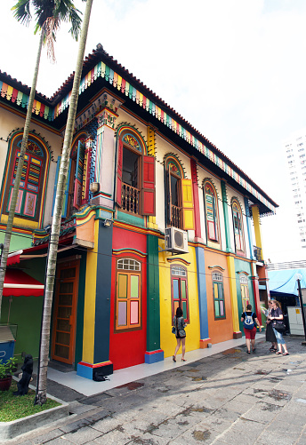 Four western tourists walking by the Tan Teng Niah house Little India Singapore. Built in 1900 this is the only ancient Chinese building left in Little India and now a tourist attraction as it is colourfully painted.