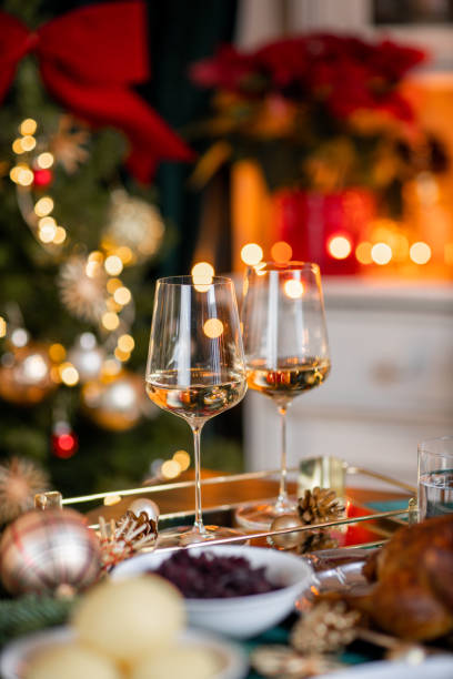 Festive Christmas dinner table with white wine glasses with roast goose turkey in cozy home stock photo