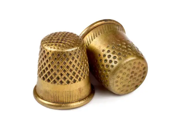 Two antique copper thimbles on a white background. Old thimbles close-up. A selective focus.