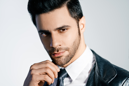 Closeup portrait of handsome trendy man posing on white studio background. Men's beauty concept