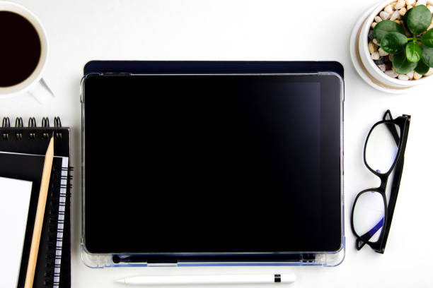 istock Top view modern white desk with tablet computer for graphic design, book pages and other accessories on  white background 1445128418