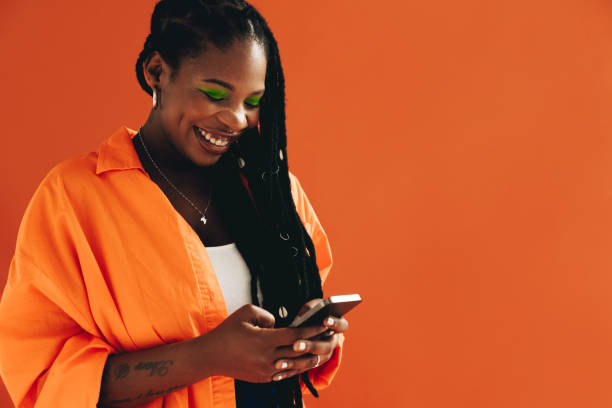 istock Smiling black woman sending a text message on her smartphone in a studio 1445128431