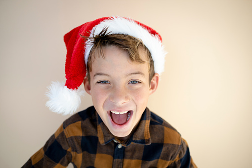 cool young boy with santa hat is posing