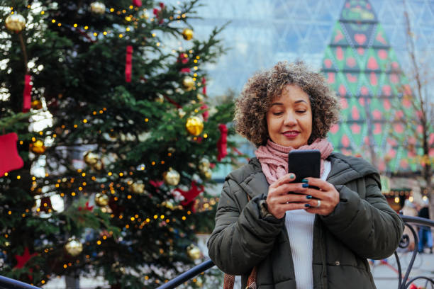 Woman using cellphone in Christmas themed city.