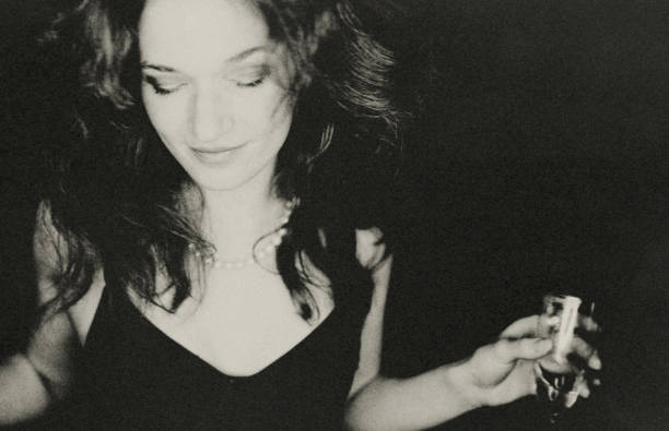 Portrait of an interesting woman in a bar. She holds a champagne flute in her hand and dances with her eyes closed.