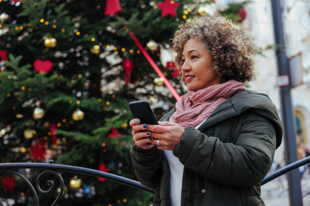istock Mature woman using mobile phone with outside with Christmas tree. 1445129961