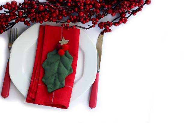 istock Festive table setting for Christmas White ceramic plate. Holly leaves and red tablecloth on  white 1445130108