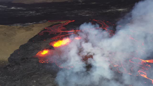 Volcano vent eruption with ejected lava river flowing down valley in Iceland