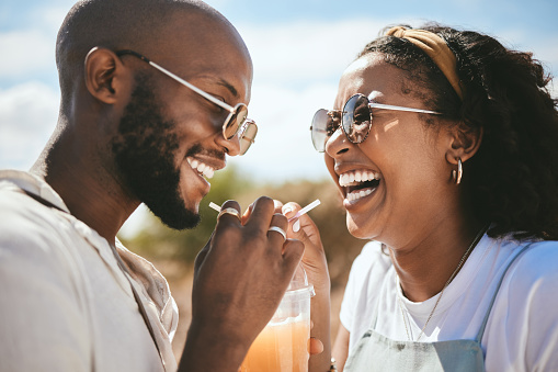 Summer, love and couple share a drink on Mexico vacation together for travel, happy and relax in nature. Romance, lifestyle and smile with man and woman drinking with straw for date, care and trip