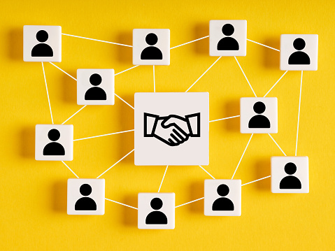 Business agreement between different parties. Business deal, cooperation and partnership network. Consensus. Cubes with network of employees and handshake symbol.