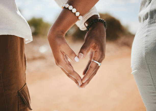 junte as mãos, o coração e o amor, a bondade e a confiança com apoio juntos ao ar livre. dedos em close-up sinal de pessoas negras moldam em relacionamento romântico, celebram lua de mel e salvam a data do casamento - romance honeymoon couple vacations - fotografias e filmes do acervo