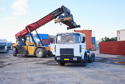 Truck, logistics and supply chain with a construction driver on a commercial container yard for shipping or distribution. Storage, stock and cargo with a vehicle in the import and export industry