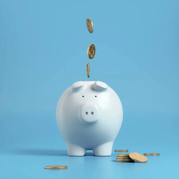 Photo of Falling coins in to a white piggy bank