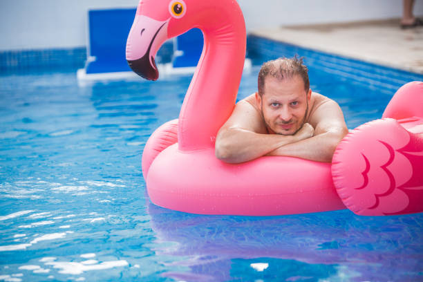 istock Cheerful man on flamingo rubber ring 1445134585