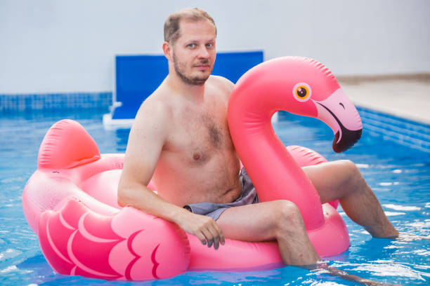 istock Cheerful man on flamingo rubber ring 1445134696