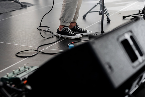 Rock star performing live on hard rock concert stage. focus on old sneakers of musician