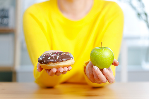 Choosing between doughnut and apple. Good nutrition for a healthy body