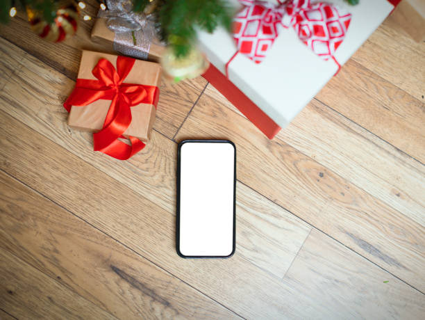 istock New Year's background with gifts under the Christmas tree, a phone with white empty space. 1445142338