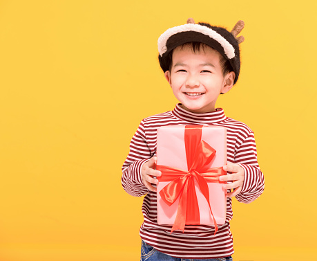 Happy little  boy dressed in winter clothes and holding gift box