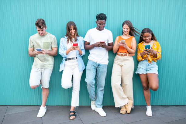 Group multiracial friends using smartphones outside