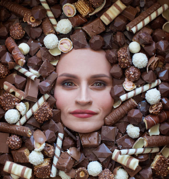 gros plan d’une belle femme sur fond chocolat brun. image conceptuelle. - brown chocolate candy bar close up photos et images de collection