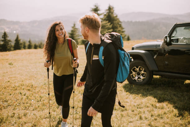 istock Smiling couple walking with backpacks over green hills 1445153105