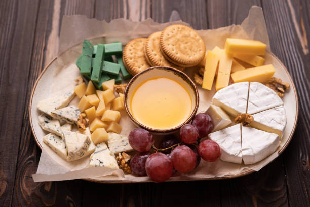 istock Cheese plate with honey, grapes and nuts on wooden table, top view, flat lay. 1445153319