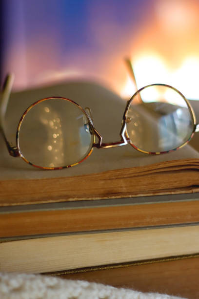 point of view of hands of an old woman holding a pair of horn-rimmed eyeglasses to solve a sight problem and reading a book.literature and reading as a hobby.myopia,presbyopia and astigmatism.