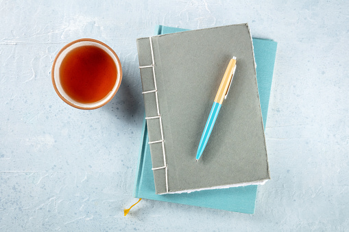 Diary. Journals with a pen and a cup of tea, overhead flat lay shot on a desk, minimalist style