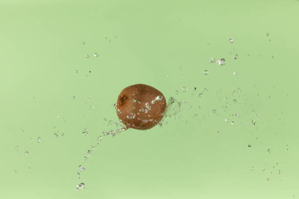 Fresh kiwi on green background with water splash