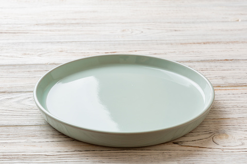 Perspective view of empty blue plate on wooden background. Empty space for your design.