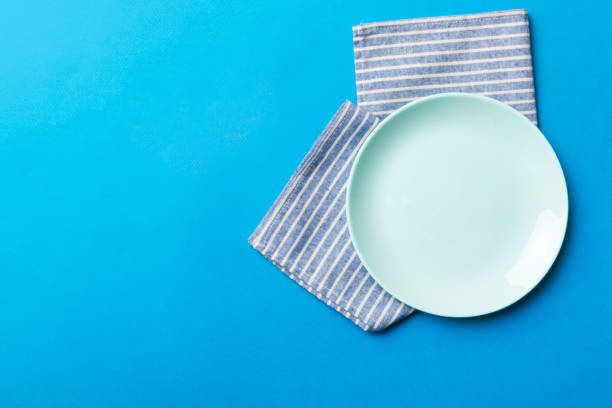 istock Top view on colored background empty round blue plate on tablecloth for food. Empty dish on napkin with space for your design 1445158863