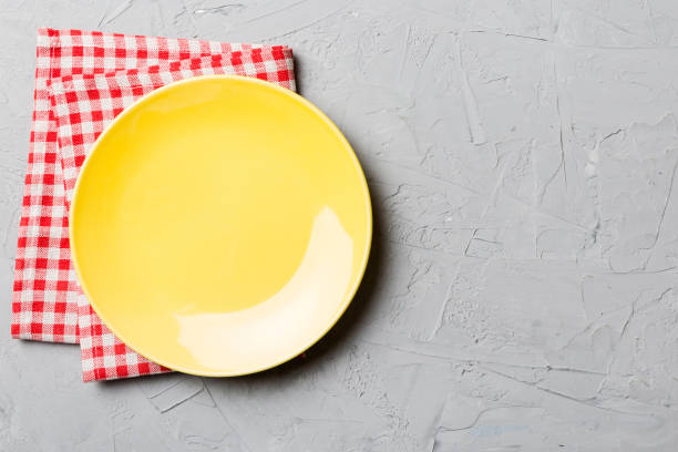 istock Top view on colored background empty round yellow plate on tablecloth for food. Empty dish on napkin with space for your design 1445158865