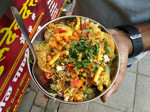 Holding Indian street food masala chaat sev puri dish