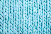 Close up above view of light blue soft wool knitted wool blanket background.