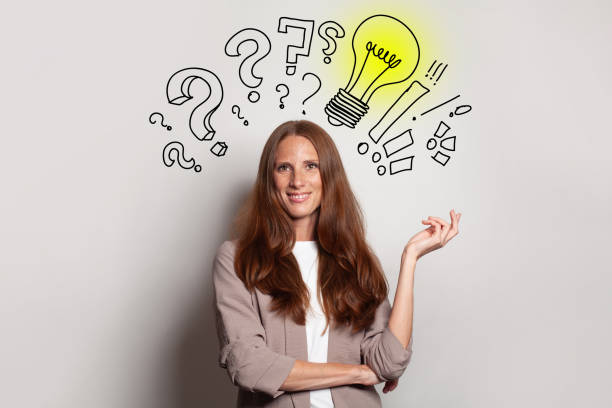 istock Smiling brunette woman with yellow light bulb, question marks above her head. Idea, brainstorming, business stratgy, thinking concept 1445162523