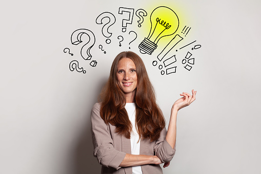 Smiling brunette woman with yellow light bulb, question marks above her head. Idea, brainstorming, business stratgy, thinking concept