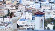 istock Asian Chinese female tourist photographing with smart phone at Chefchaouen townscape 1445166063
