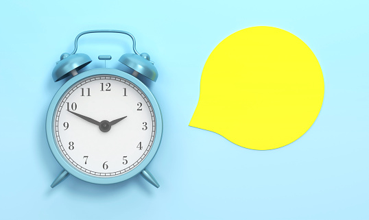Empty Yellow speech bubble and Blue Alarm Clock On The Blue Background. Time Concept.