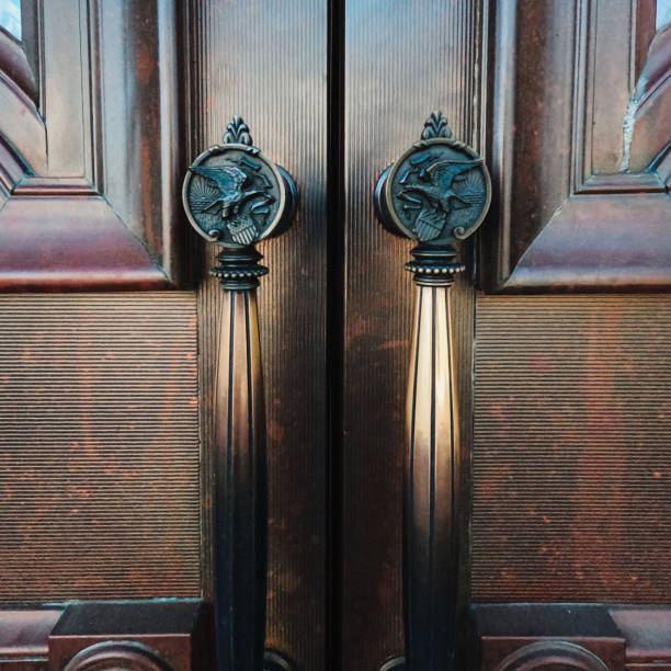 The Illinois State Capitol Building in Springfield, Illinois, USA Closeup View of the handles to ornate wooden doors located at the West entrance to the Illinois State Capitol Building in Springfield, Illinois, USA. State of Illinois seal is engraved onto the knobs of the brass handles. Depicts a bald eagle holding a waving banner. illinois state capitol stock pictures, royalty-free photos & images