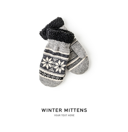 Winter warm mittens with christmas snowflakes. Knitted gray gloves isolated on white background. Creative layout. Flat lay, top view. Design element