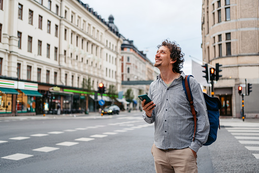 Handsome young man walking on the street and using his smart phone in Stockholm, Sweden.