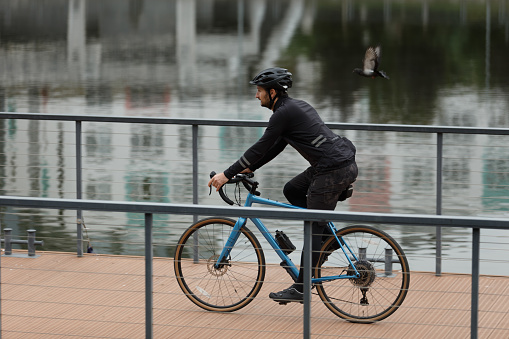 Daily cardio cycling workout. A cyclist in winter clothes rides along the river.