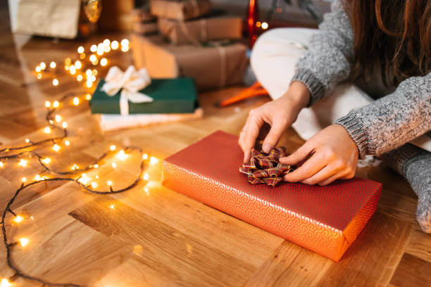 istock A woman adding a bow on top of a Christmas gift box 1445178893