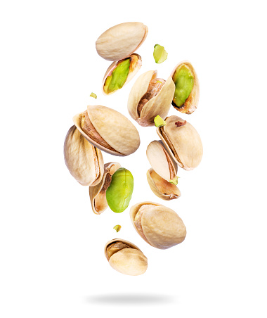 Whole and crushed pistachios close-up in the air on a white background